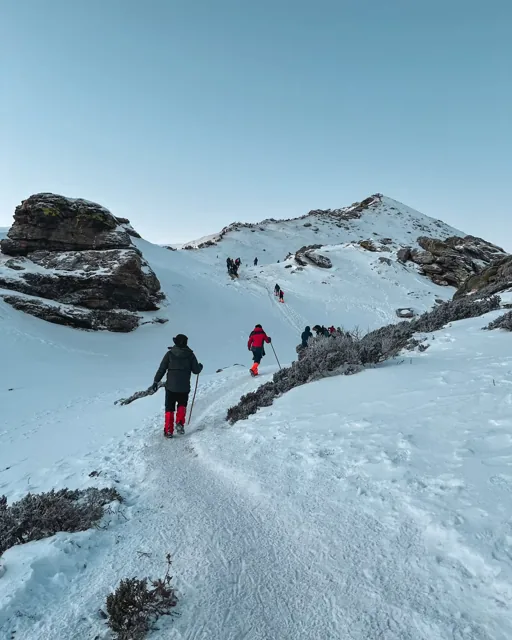 Trekkers walking through a snowy Himalayan landscape